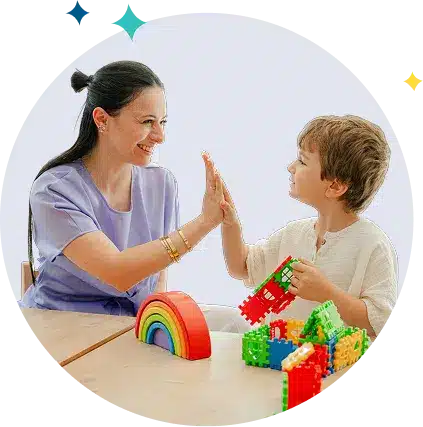 Une professionnelle de santé et un enfant se font un check, entourés de jeux et jouets éducatifs.